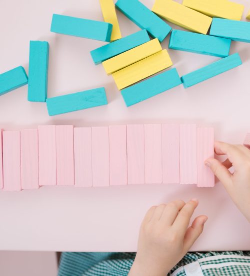 Lovely kids plaing with colorful wodden blocks in a creative educational game as they stand at a pink table
